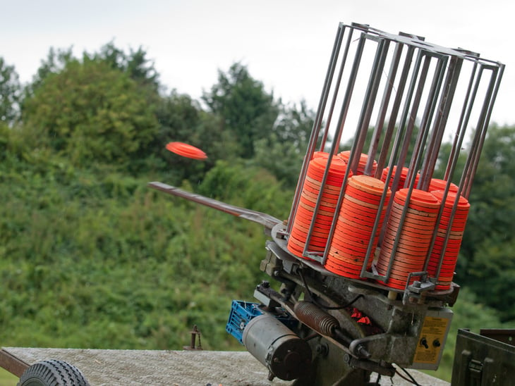 A clay pigeon is ejected out of a clay target machine